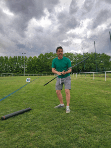 a man in a green shirt is holding a long pole