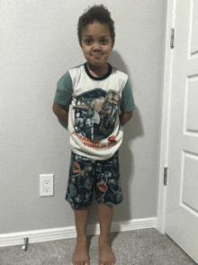 a young boy wearing a jurassic world shirt and shorts