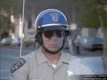 a police officer wearing a helmet and sunglasses is standing on the street .