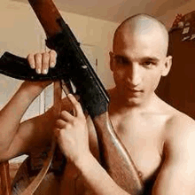 a shirtless man is holding a rifle in his hands .