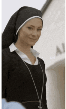 a woman in a nun costume is smiling and wearing a cross around her neck