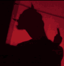 a shadow of a person with horns is giving the middle finger