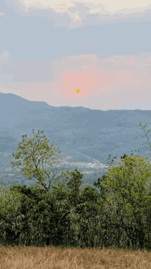 a sunset over a valley with trees and mountains in the background