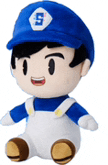 a stuffed toy of a boy wearing a blue hat and overalls is sitting on a white surface .