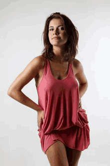 a woman in a pink tank top and short skirt is standing with her hands on her hips .