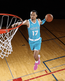 a basketball player wearing a hornets jersey jumps in the air