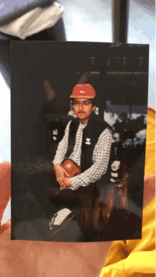 a photo of a man wearing a red hat and a vest with the letter h on it