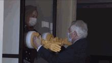 a man wearing a mask and gloves is talking to a woman wearing a face mask