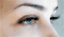 a close up of a woman 's eyes with long eyelashes and a tear coming out of her eye .