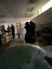 a group of people standing around a globe in a room