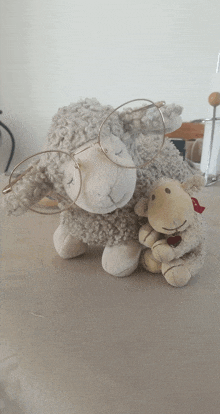 a stuffed sheep wearing glasses and holding another stuffed sheep