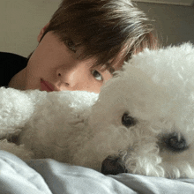 a man is laying on a bed with a white dog