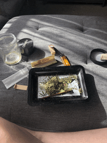 a tray of marijuana sits on a couch next to a grinder that says ' oziro ' on it