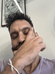 a man covering his face with his hand in front of a framed picture that says barbers of america