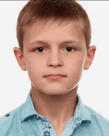 a young boy wearing a blue shirt with flowers on it