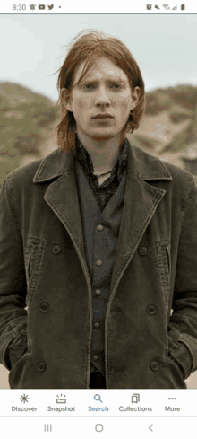 a man with red hair is standing in front of a sand dune with the time of 8:30