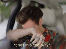 harry styles is crying in a car while wearing a floral shirt .