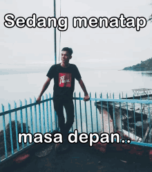 a man standing on a balcony overlooking a body of water with sedang menatap masa depan