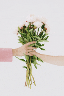 a woman in a pink jacket holds a bouquet of flowers