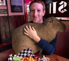 a man holding a capybara in front of a sydney cricket ground sign