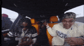 a man wearing a los angeles jersey is sitting in the back seat of a car with another man