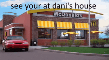 a red car is driving past a mcdonald 's