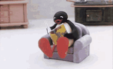 a penguin sits in a chair reading a book called penguins