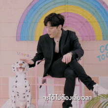 a man in a black suit is sitting on a pink chair with a dalmatian dog .