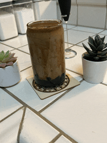 a glass of coffee sits on a coaster on a tiled counter