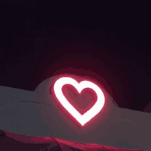 a red heart is lit up on a building at night