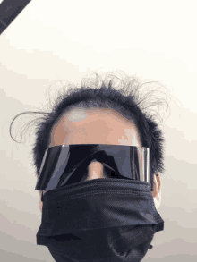 a person wearing a mask and sunglasses looks at the camera