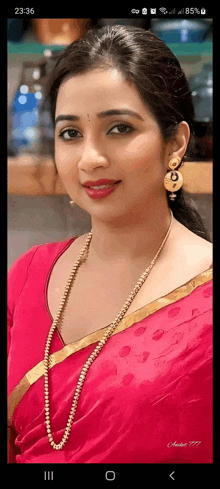 a woman in a pink saree is wearing a gold necklace .