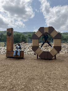 two people sit on a bench next to a large wooden l