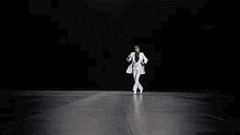 a man in a tuxedo and white ruffled shirt is dancing in a room .