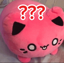 a pink stuffed animal with three red question marks on its face