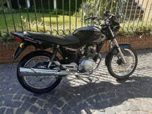 a black honda motorcycle is parked on a cobblestone street