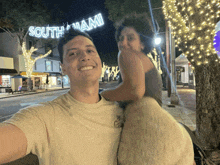 a man carrying a woman on his shoulders in front of a south miami sign