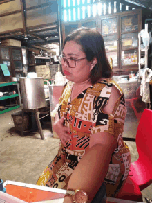 a woman wearing glasses and a dress that says ' u.s.a. ' on it sits at a table