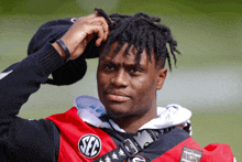 a man with dreadlocks is wearing a red and black shirt that says sec