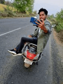 a man is sitting on the back of a scooter taking a selfie .