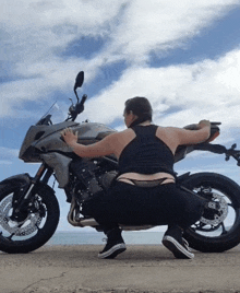 a woman is squatting next to a motorcycle that says yamaha on it