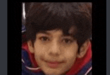 a close up of a young boy 's face with a red sweater on .