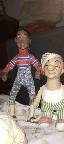 two dolls standing next to each other with one wearing a striped shirt and suspenders