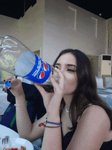 a woman drinking from a bottle that says pepsi on it