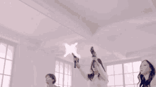 three women are holding up guns in a room with a white ceiling .