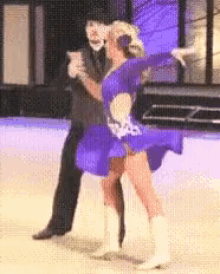 a woman in a blue dress is dancing with a man in a suit and cowboy boots