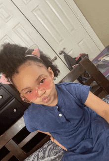 a little girl wearing sunglasses and a cat ear headband makes a funny face