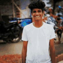 a young man wearing a white t-shirt is smiling for the camera