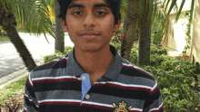 a young man wearing a striped shirt with a crest on the front