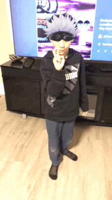 a person wearing a black puma sweatshirt stands in front of a television